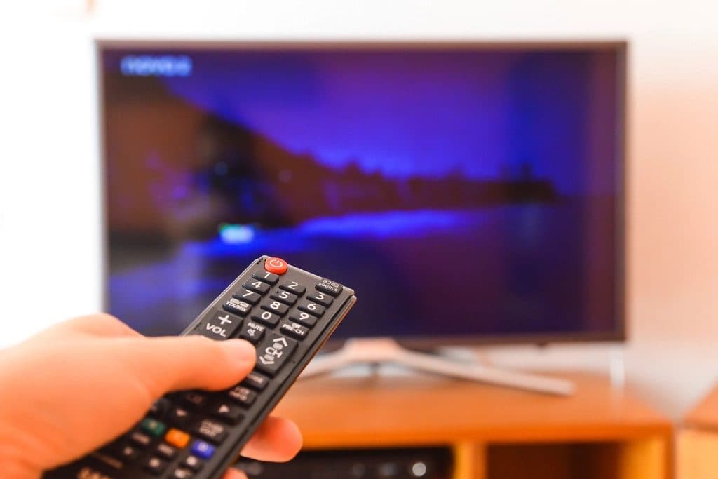 A hand pointing a remote control at a television