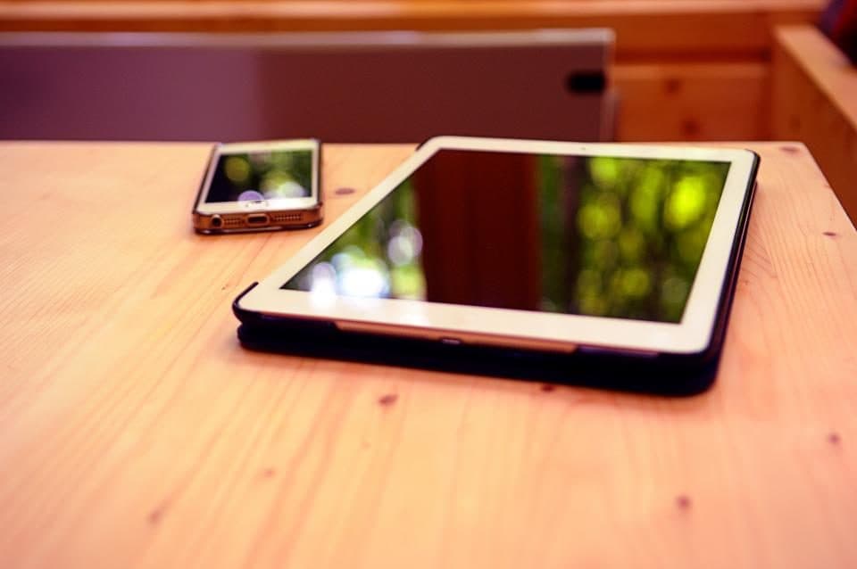 An iPad and an iPhone lying on a wooden table